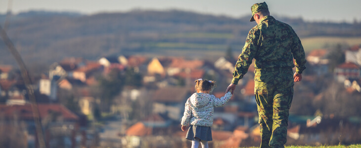 soldier and his daughter walking on a grass field